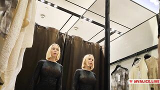 A mischievous 20-year-old blonde with beautiful size 4 tits films herself on a smartphone in the reflection of a mirror, trying on transparent clothes in a store