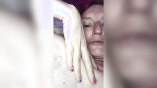 Ein Mann filmt eine rothaarige reife Frau in einem T-Shirt auf einem Smartphone mit einer Nahaufnahme, die mit den Fingern masturbiert, um ihre eingewachsene Muschi zu masturbieren